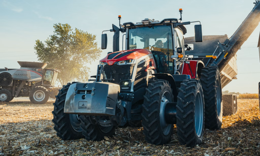 Massey Ferguson 9S pulling a Grain Cart with a Massey Ferguson Gleaner combine in the background.